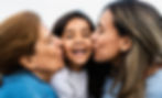 mother and grandmother kissing a child on the cheeks