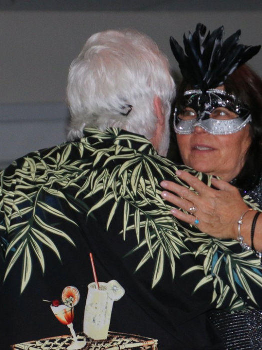 couple dancing, one has a purple and silver Mardis Gras Mask on