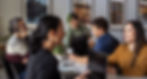 several individuals sitting at a table chatting and working