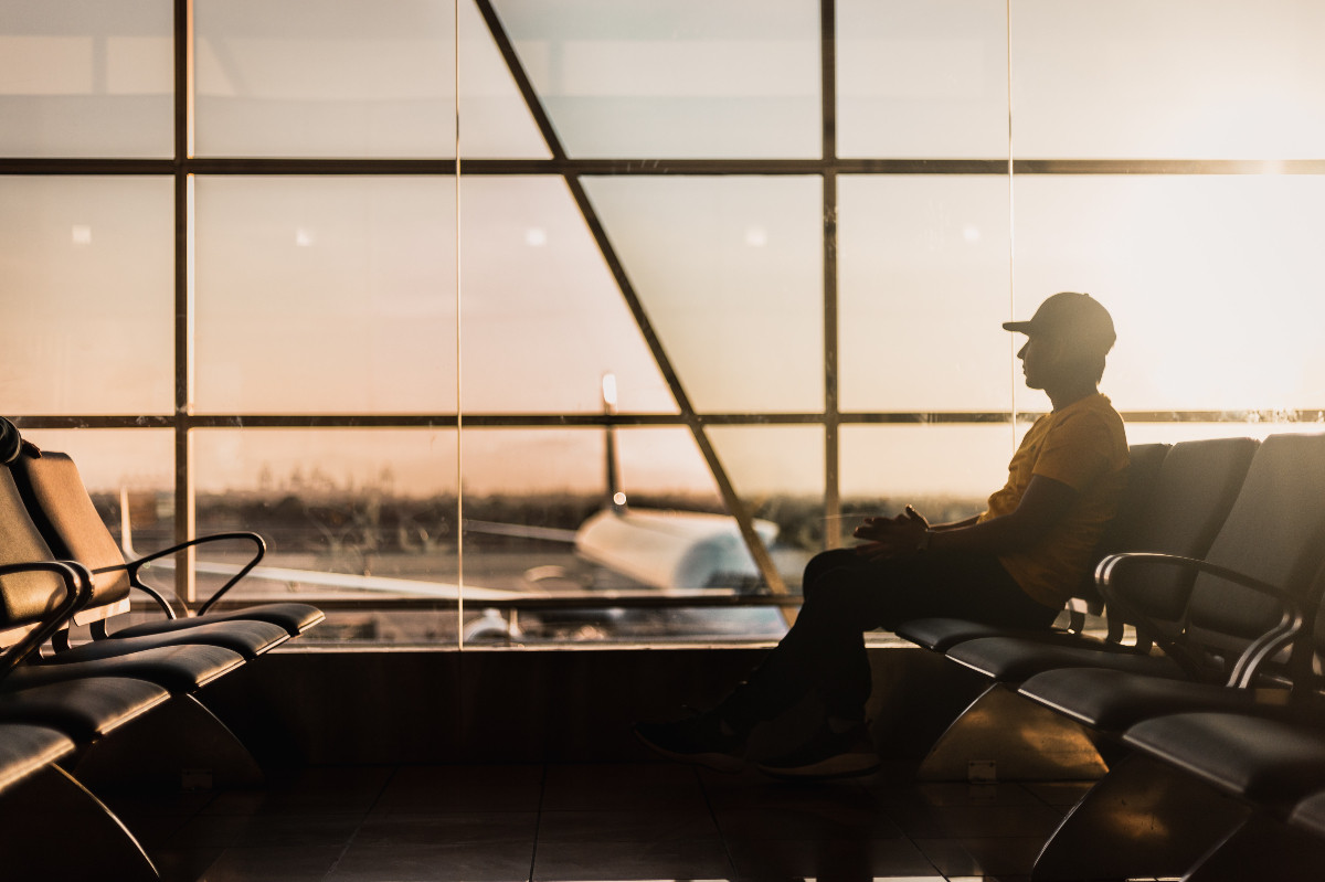 Pessoa triste no aeroporto representando a tristeza em imigrar