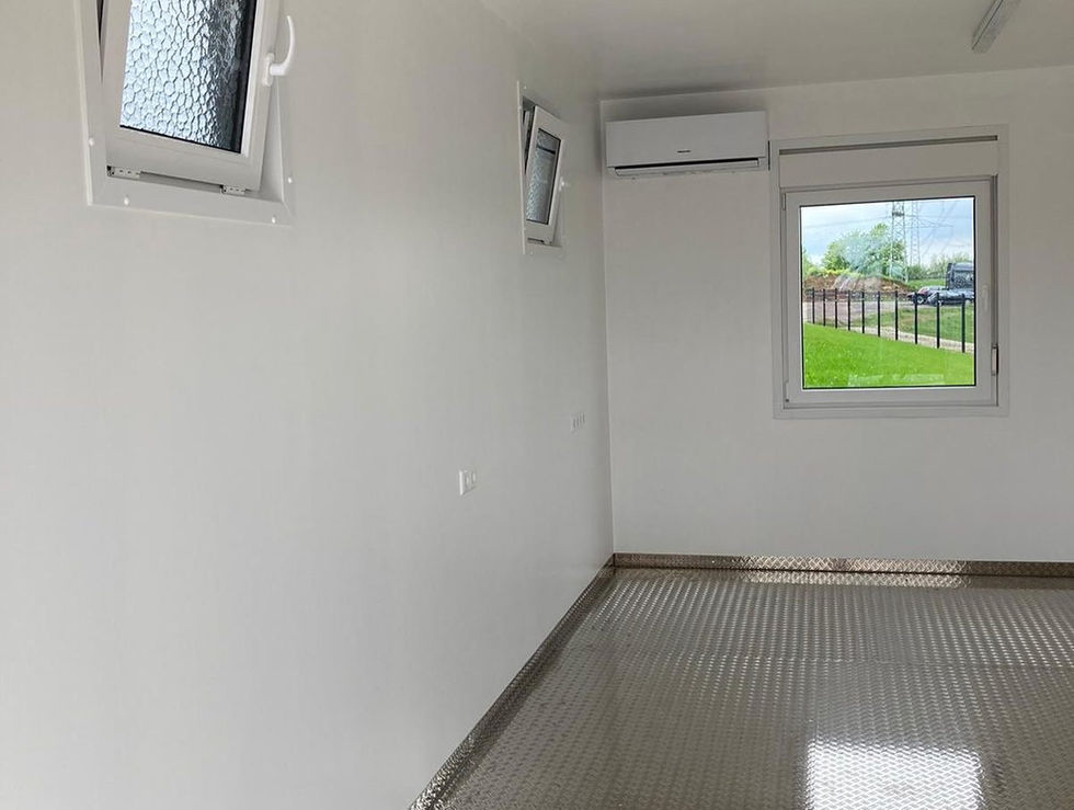 Fertiger Innenraum mit weißen Wänden, Riffelblech-Boden, Klimagerät und Fenster mit Grünblick.