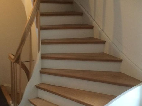 Präziser Treppenbau: Moderne, gewendelte Holztreppe mit massiven Eichenstufen und weiß lackierten Setzstufen.