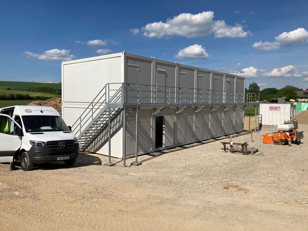 Weiße zweigeschossige Containeranlage mit Außentreppe, davor ein Firmentransporter der Holztechnik Neumann.