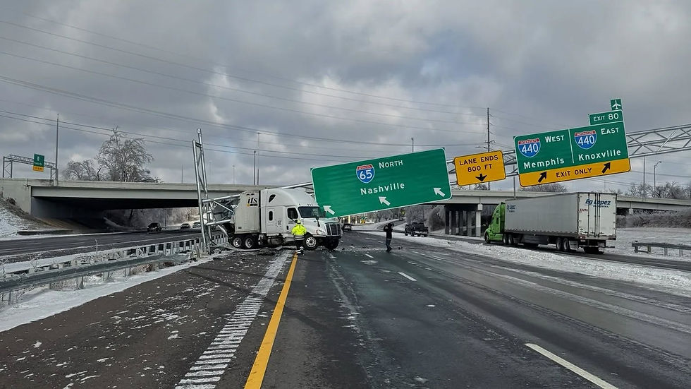 Truck crashed into Nashville highway sign, blocking lanes. Overcast sky, icy road, and a green truck in the background.