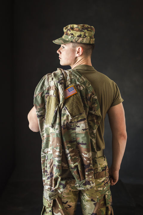 Soldier posing with jacket, camo uniform, looking left, dark background in studio. Lbshoots