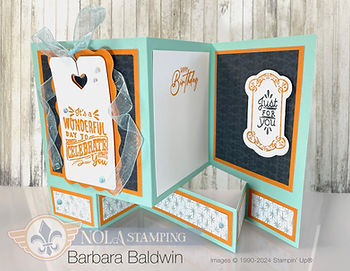 Folded birthday card with orange and teal layers, ribbon, and text: It's a wonderful day to celebrate you. Background has wood texture.