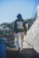 person in sporty attire walking up stairs outside wearing Coastal Sun hoodie and dad hat