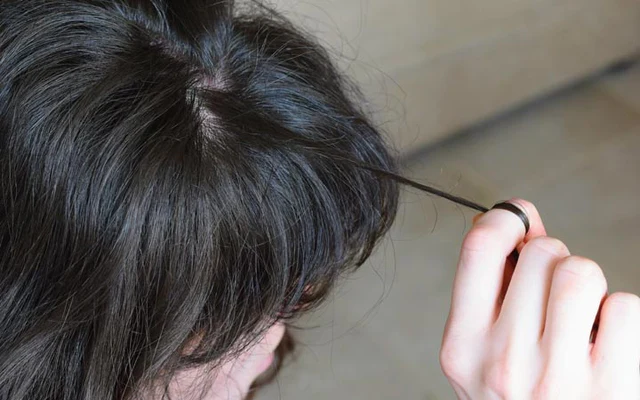 a person cutting hair with a black comb