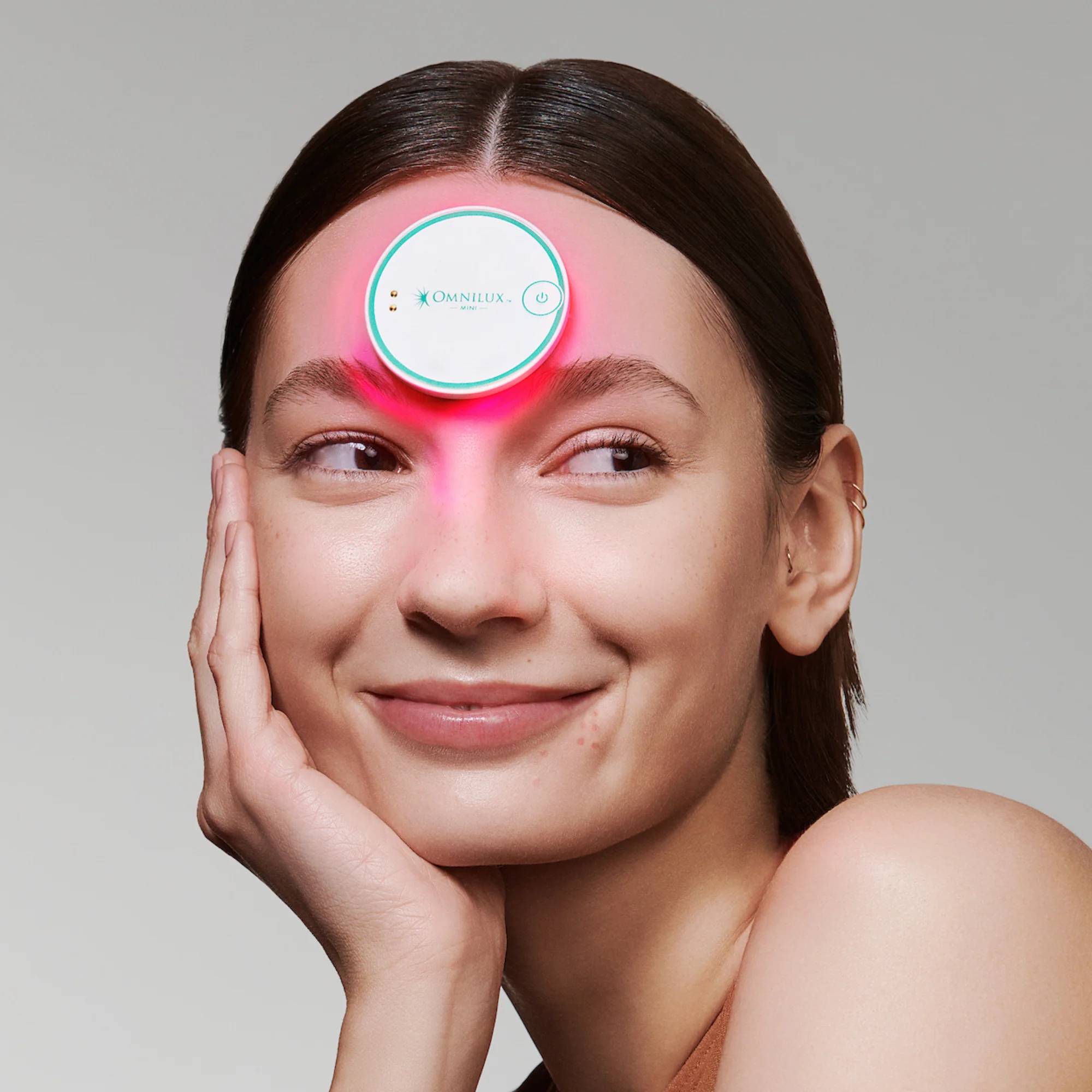 Woman wearing Omnilux: Trusted LED therapy on her forehead, for blemish control