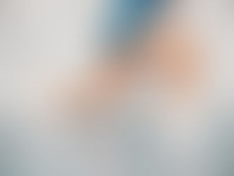 Person in blue shorts lunging on a gray wooden floor. Wearing white sneakers. Background is a textured gray wall.