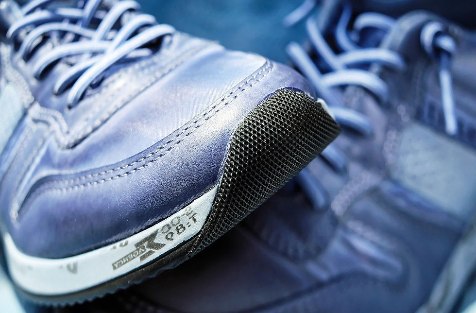 Close-up of blue athletic shoes with detailed stitching, textured black toe caps, and visible brand text, showing a sporty mood.