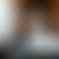 Woman in black workout attire adjusting top in a modern bedroom with a large bed and window. Black-and-white photo on the wall. Cozy mood.