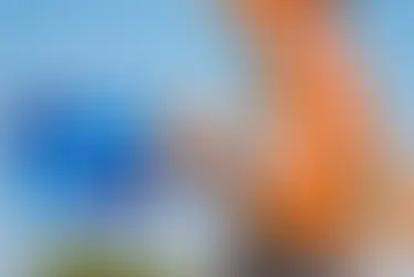 Runner in a white tank top using a smartwatch with heart rate icon overlay. Clear blue sky background. Focus on arm and watch.