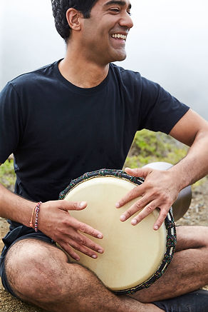 A profile image of Neil Wadhawan, and SF yoga teacher, seated and playing the djembe