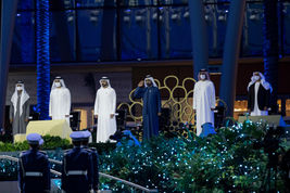 Top event photographer capturing Gulf leaders on stage at a night ceremony, saluting honour guard amid blue lights and greenery