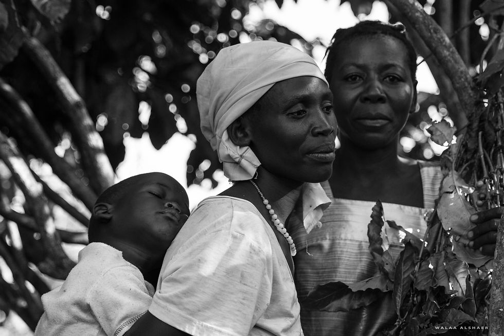 Cultural Documentaries – black-and-white portrait: two women and a child asleep on his mother’s back under trees; an intimate family bond.