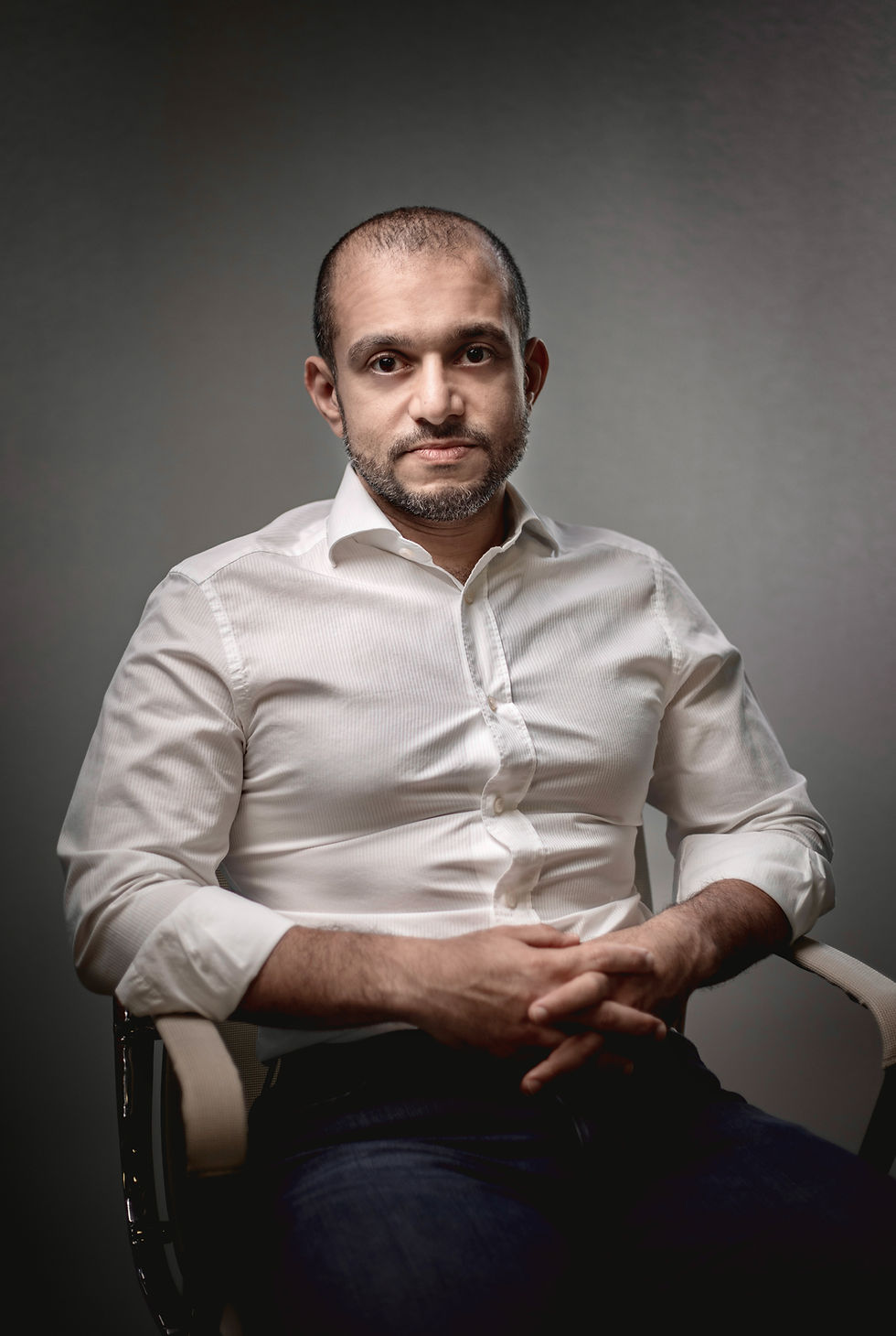 black and white portrait photography artists inspired studio portrait of a man in a white shirt, dramatic soft light, and a minimal gray background.