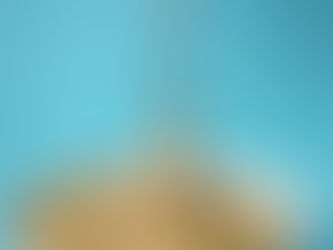 Creative food styling shot of creamy pasta twirled on a fork over a blue background, highlighting color contrast and appetizing texture.