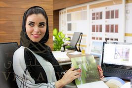 corporate photography of Arab businesswoman in modern office reviewing design catalog and smiling at camera