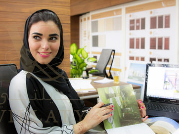 corporate photography of Arab businesswoman in modern office reviewing design catalog and smiling at camera