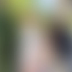 Woman in purple dress holding a laughing boy in a white jacket. Greenery in the background, sunlit and joyful mood.