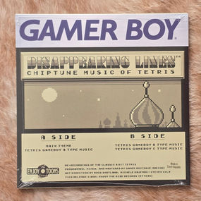 Game Boy between a music cartridge and a stack of chiptune records
