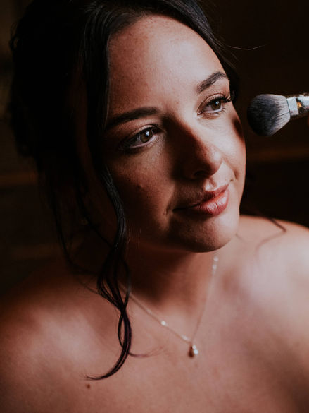 bride getting her make up done, already in wedding dress