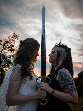 two LGBTQIA+ brides holding a sword together 