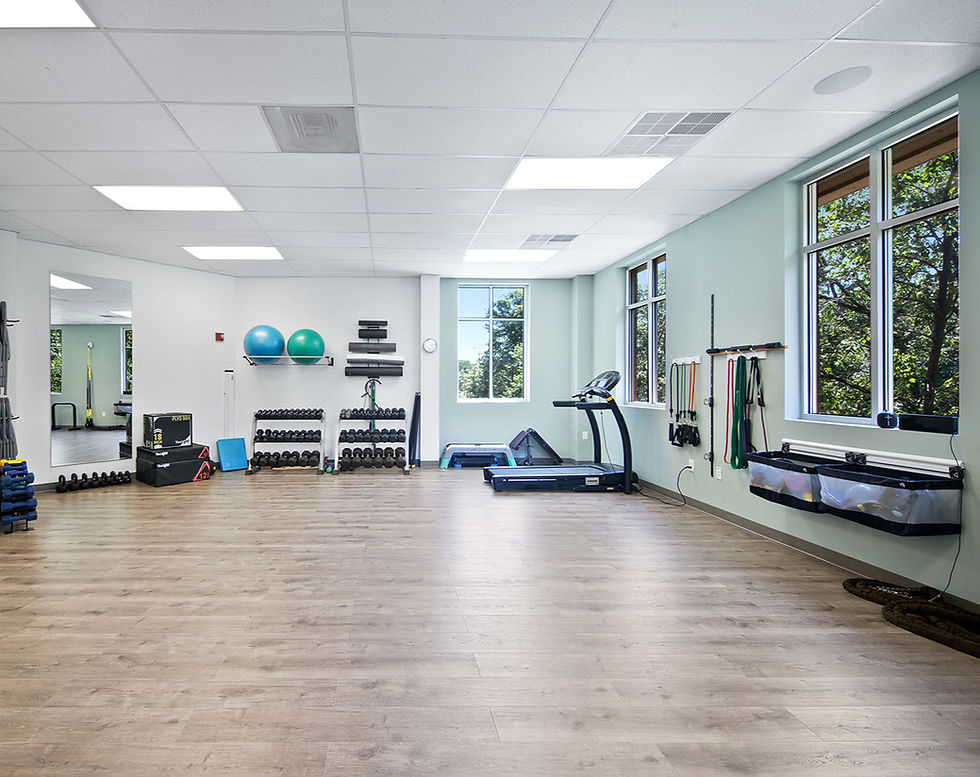 Proactive Motion Physical Therapy gym space with weights, mirrors, and therapy equipment.