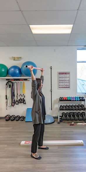 Dr. Gillespie demonstrating an overhead press to her patient during a physical therapy session in Huntersville, NC