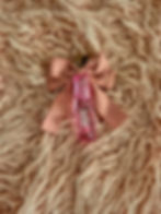 Pink lip gloss with a bow on a pink fluffy background. Ph Pink Lip Stain Gloss.