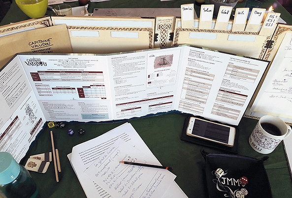 Table de jeu de rôle côté MJ avec écran, scénario, notes, dés et pistes à dés