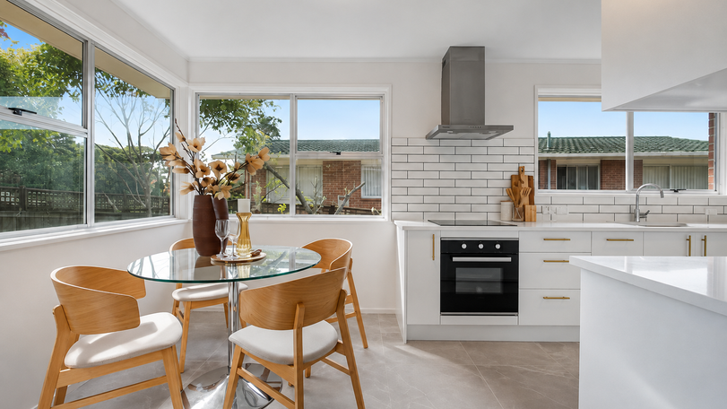 Completed white galley kitchen in Glenfield, Auckland, with E102 White Ice benchtop and gold square handles — view 2.