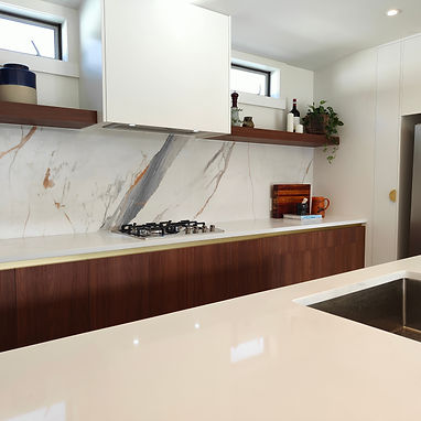 G-shaped kitchen with woodgrain base cabinets, white overhead cabinets and an island sink in Mount Albert.