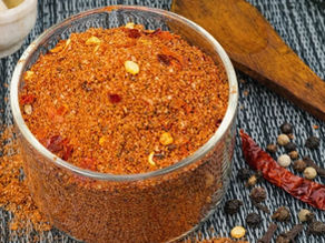 साबुत मसालों से बना घर का स्ट्रीट स्टाइल चाट मसाला पाउडर, कांच के बाउल में रखा हुआ, साथ में जीरा, काली मिर्च, लौंग और साबुत लाल मिर्च