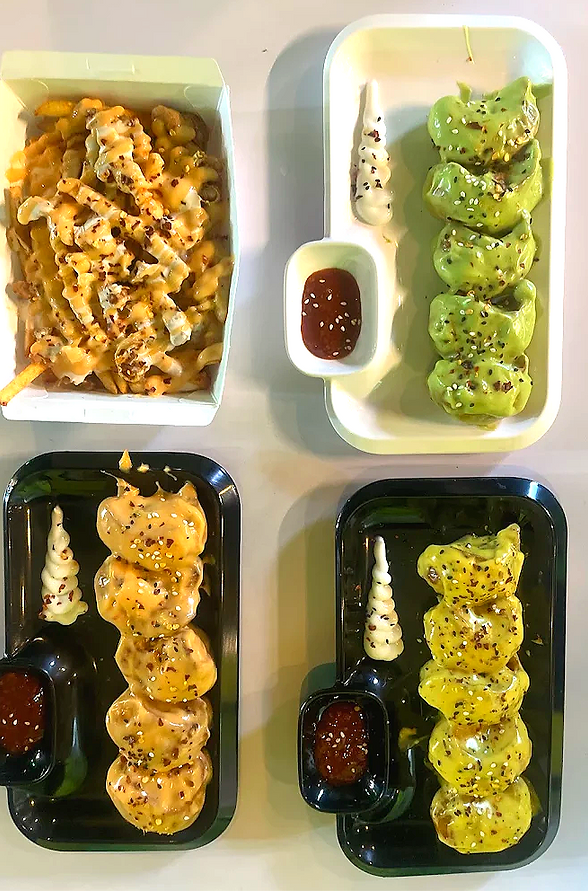 Variety of momos with colorful sauces and loaded cheese fries at Momo Popz Ottapalam.
