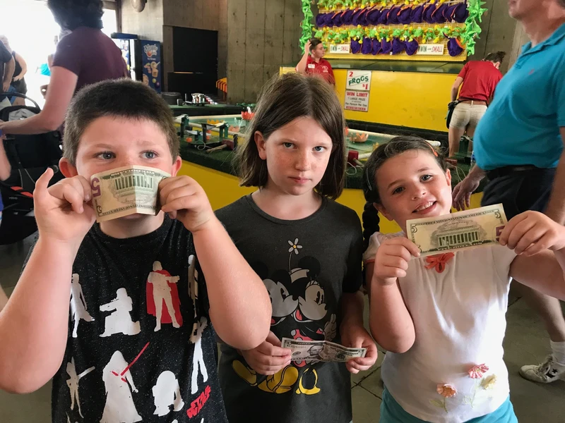 three kids holding up $5 bills