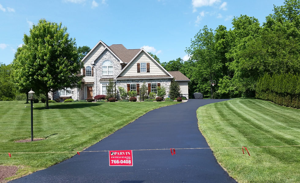 Overhead view of a damaged asphalt driveway with cracks and a small pothole