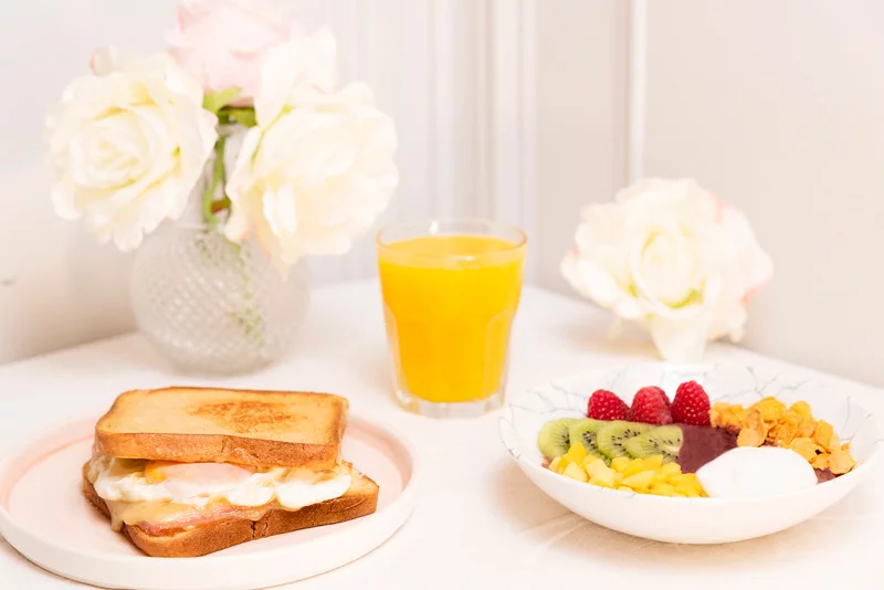 Brunch de "Mi habitación favorita" con zumo, un sándwich y un bowl con frutas 