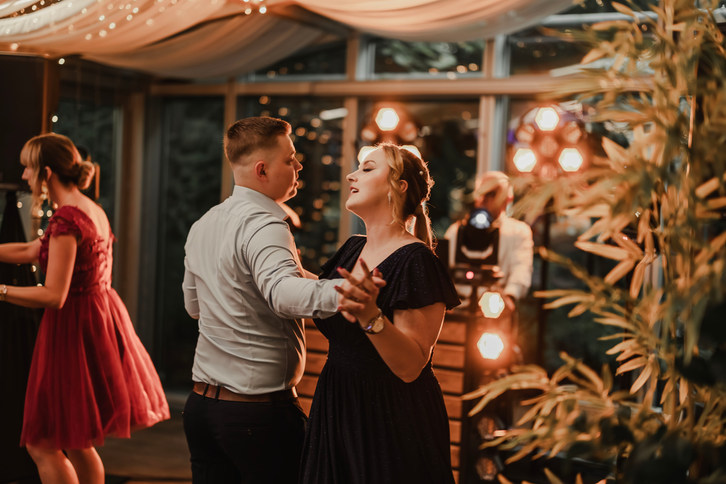 Fotograf ślubny Poznań- Para tańcząca z bliska na ciepło oświetlonej sali weselnej.