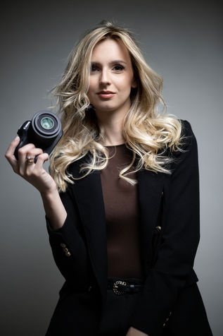 Kobieta trzyma aparat fotograficzny, sesja biznesowa. kesjastępka-fotograf. Zdjęcie studyjne.