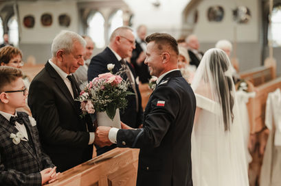 Pan młody odbiera bukiet od mężczyzny podczas ceremonii, reportaż ślubny kesjastępka-fotograf.