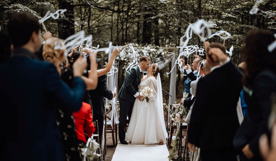 Panna młoda i pan młody całują się podczas ślubu, tło leśne.