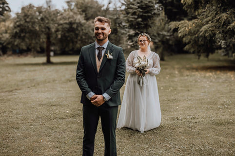 Uśmiechnięty mężczyzna czeka na pannę młodą w białej sukni, ślub w lesie. kesjastępka-fotograf