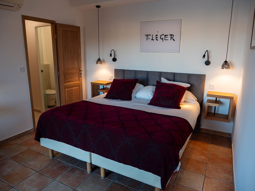 Chambre avec lit double, jeté bordeaux et tableau Fléger.