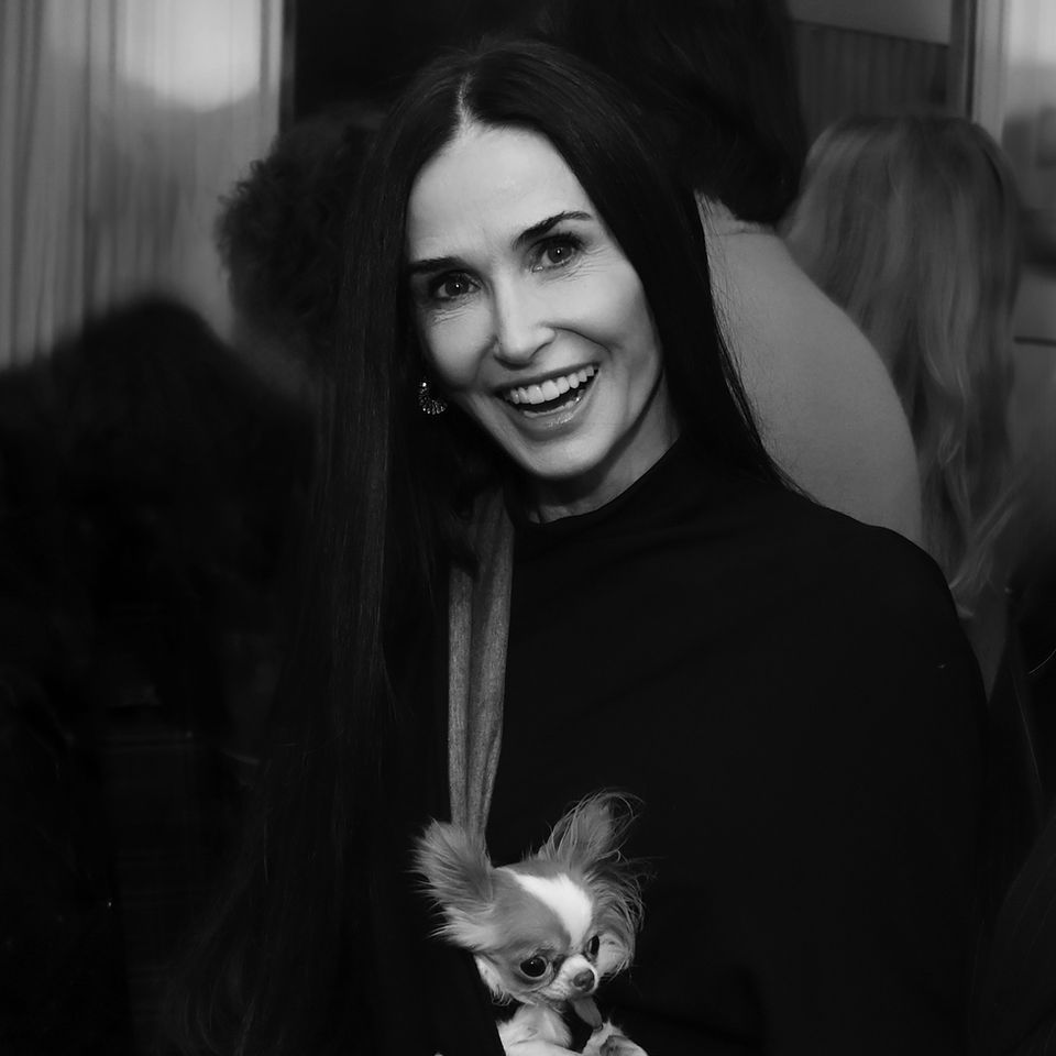 Demi Moore smiling and holding a small dog