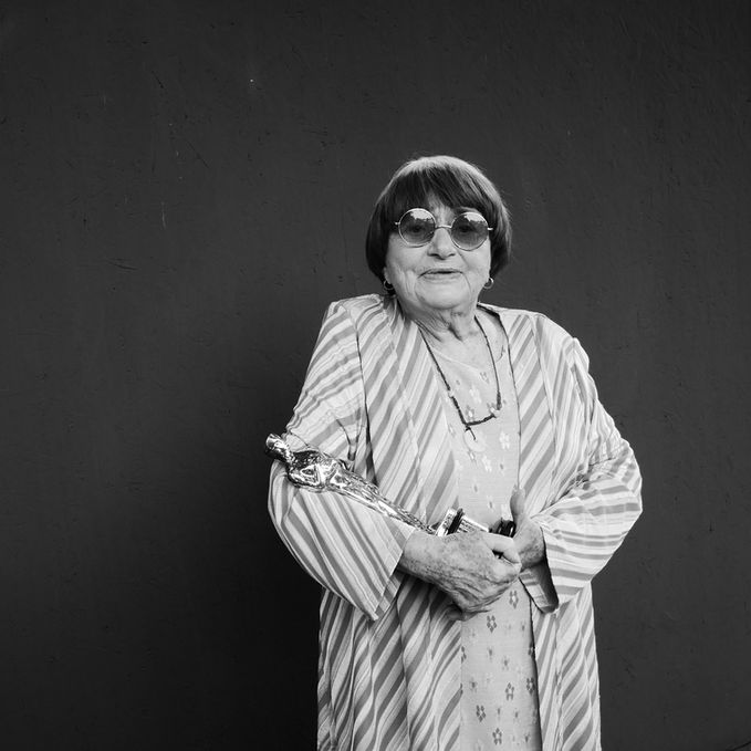 Woman in sunglasses, striped coat, holding camera