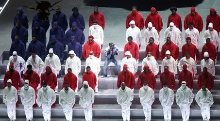Rapper Kendric Lamar posing between dancers dressed in the colors of the American flag