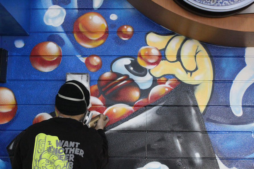 <img src="mural.jpg" alt="大阪・新世界のくら寿司に描かれたKACの壁画。">