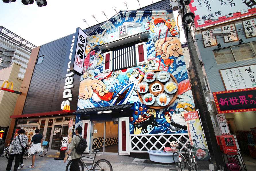 <img src="mural.jpg" alt="大阪・新世界のくら寿司に描かれたKACの壁画。">